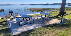 A picnic area with tables and chairs by a lake. - Lake Dora cabana with pool, hot tub and dock (Tavares)