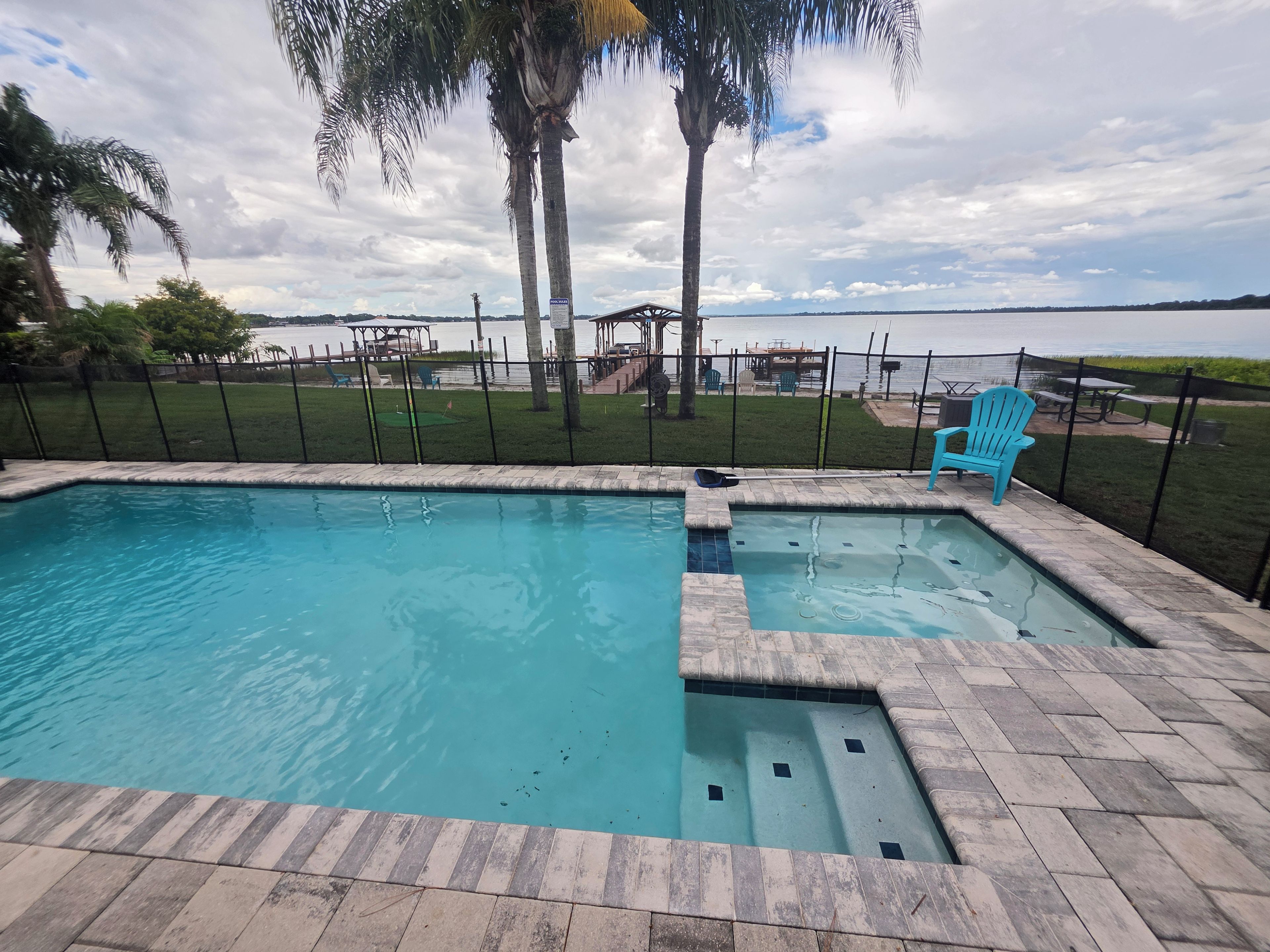 A swimming pool with a view of the lake and palm trees.