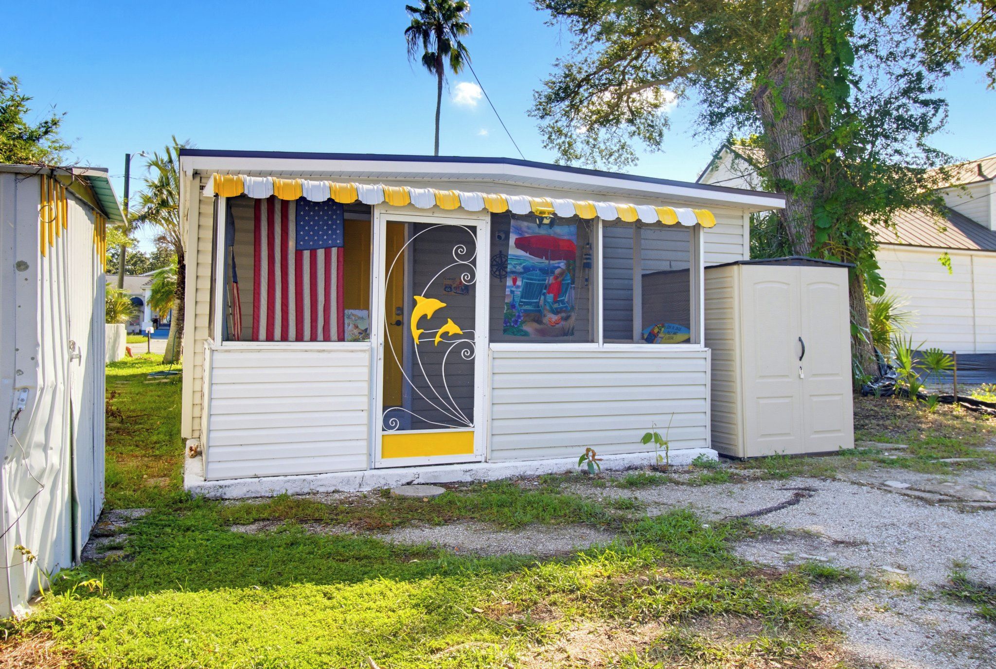 A small, single-story mobile home with a front door featuring a decorative glass panel with dolphins and a mural.