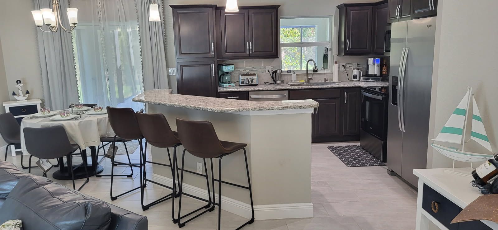 A modern kitchen with dark cabinetry, a granite countertop, and a built-in island with bar stools.