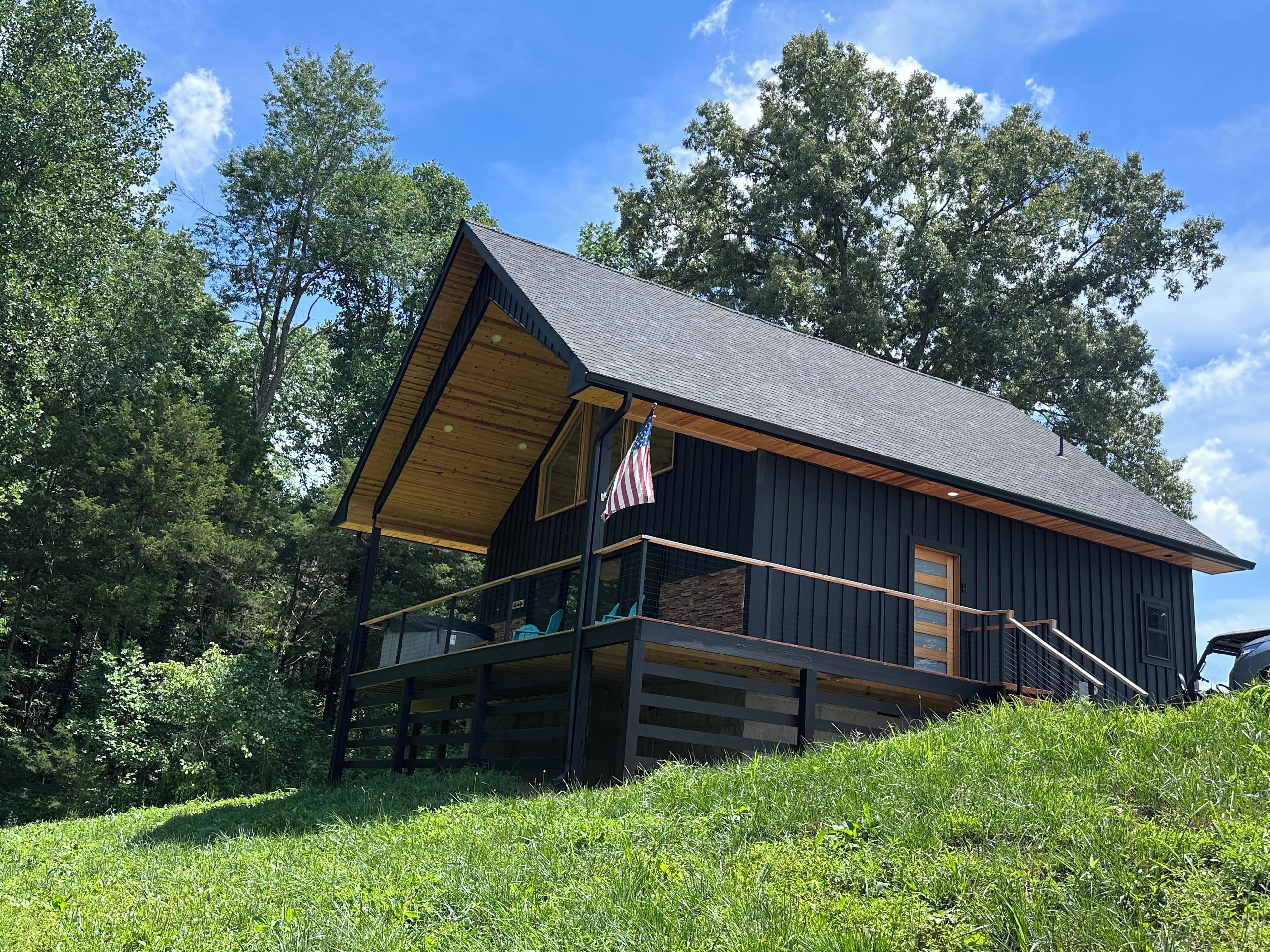 A cabin with a sloped roof, a balcony with a railing, and an American flag.