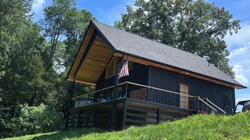 A cabin with a sloped roof, a balcony with a railing, and an American flag.