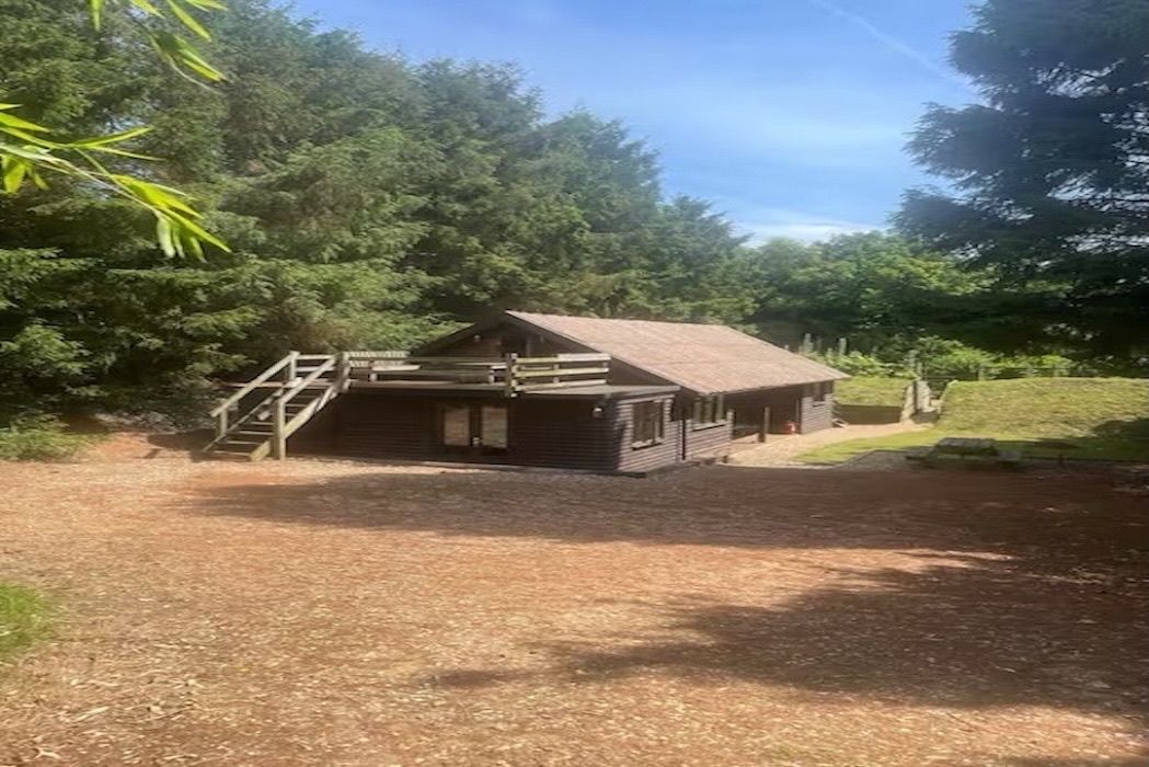 A rustic cabin with a wooden exterior, a porch, and a staircase leading to an upper level.