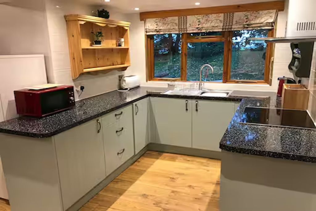 Una cucina con forno a microonde, lavello e pensili in legno.