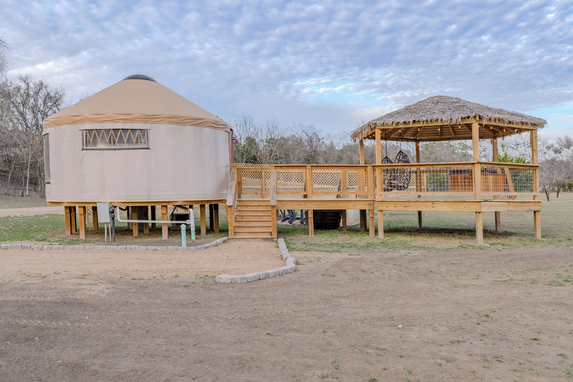 A yurt with a wooden deck and a thatched roof structure.