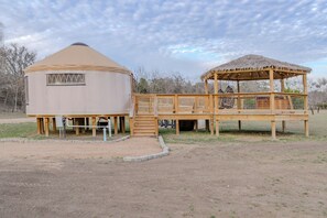 Una yurta con terraza de madera y tejado de paja.