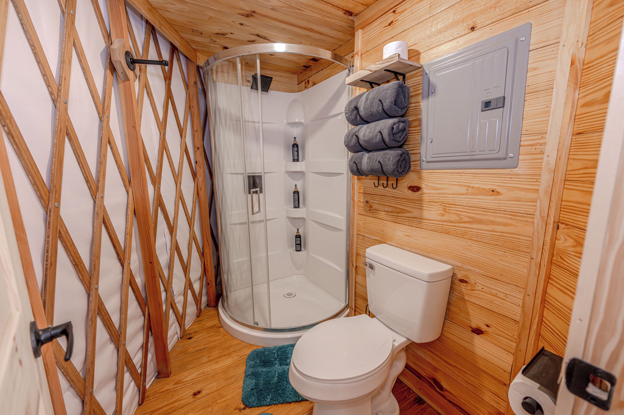 A compact bathroom with a glass shower enclosure, a toilet, and a towel rack.