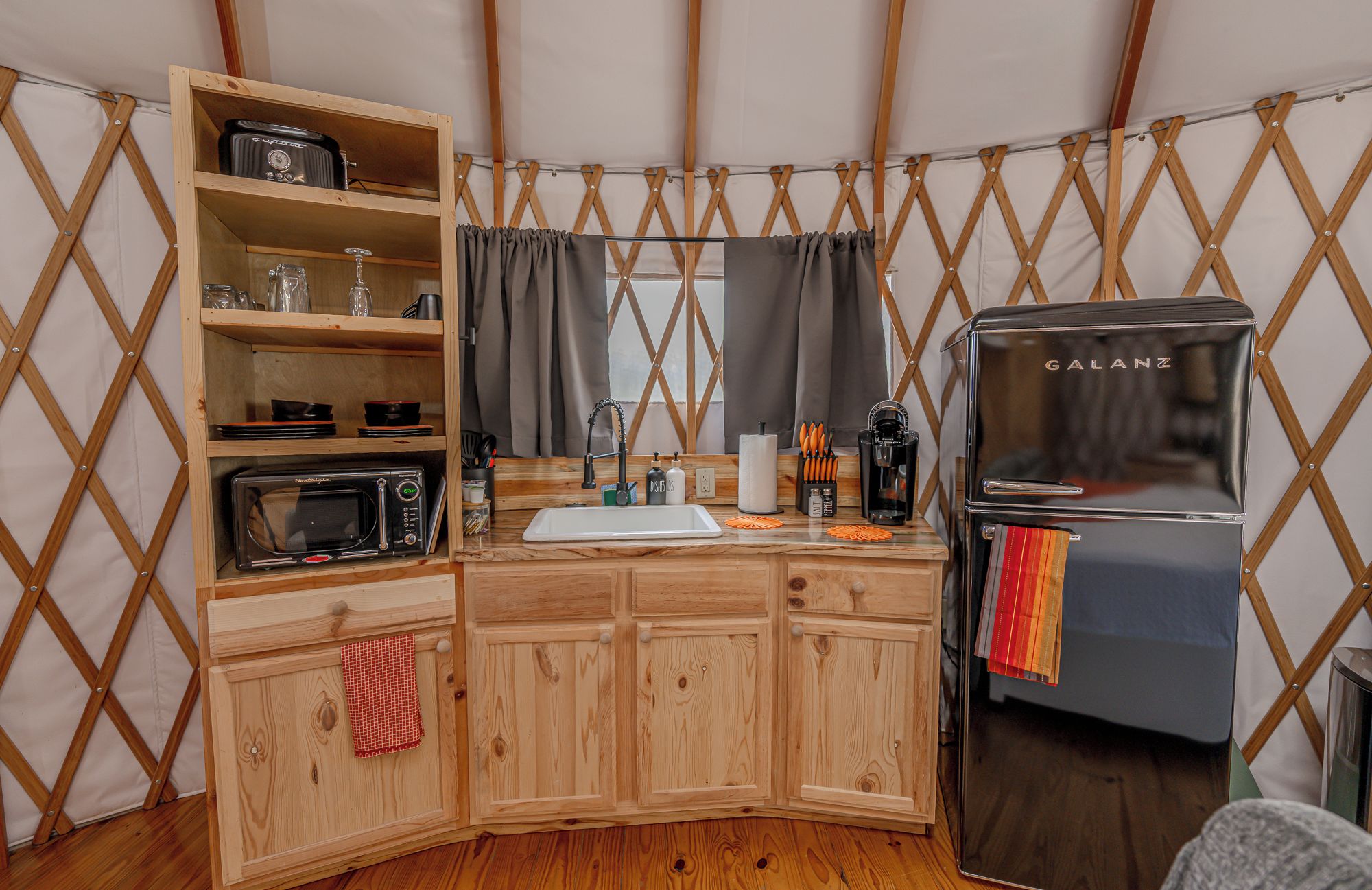 A compact kitchen with a microwave, toaster, and Galanz refrigerator.
