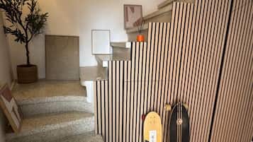 A staircase with a wooden finish, a potted plant, and two skateboards leaning against a wall with vertical wooden slats.