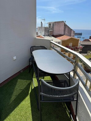 A balcony with a table and chairs, a view of the sea, and buildings in the background. - La Casita - Aguarda - Pontevedra (A Guarda)