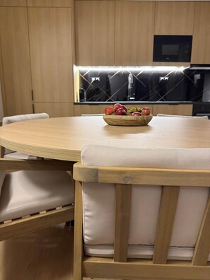 A modern kitchen with a round dining table, wooden chairs, and a bowl of fruit on the table. - La Casita - Aguarda - Pontevedra (A Guarda)