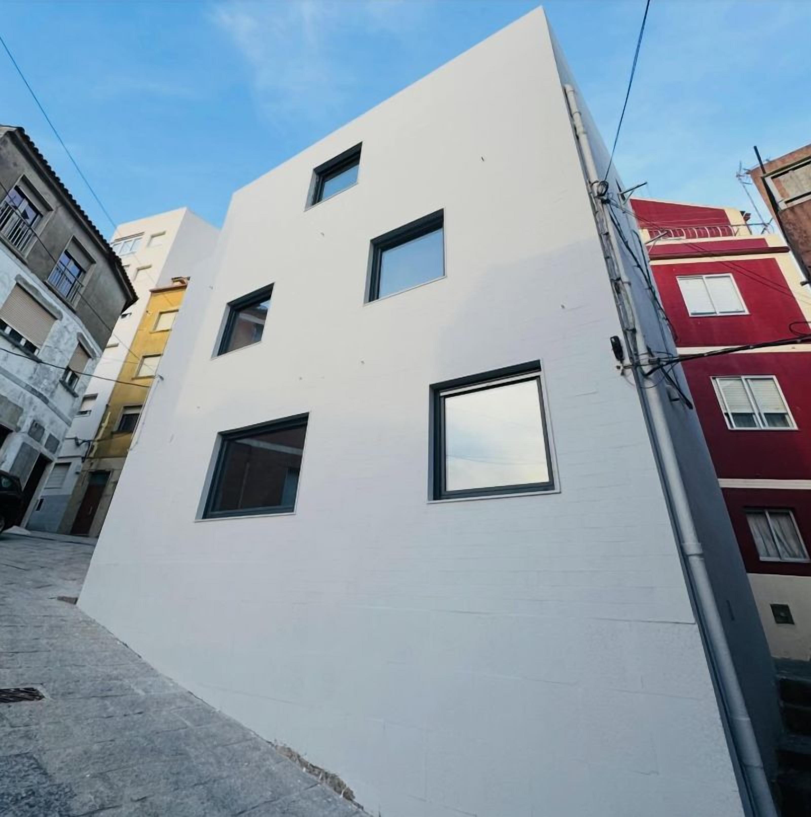 Un bâtiment moderne à la façade blanche et aux nombreuses fenêtres.