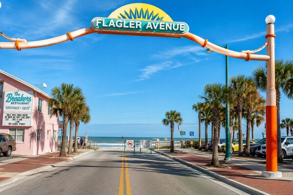 Straßenansicht mit einem Schild für Flagler Avenue, der Straße gesäumt von Palmen, und einem Strand im Hintergrund.