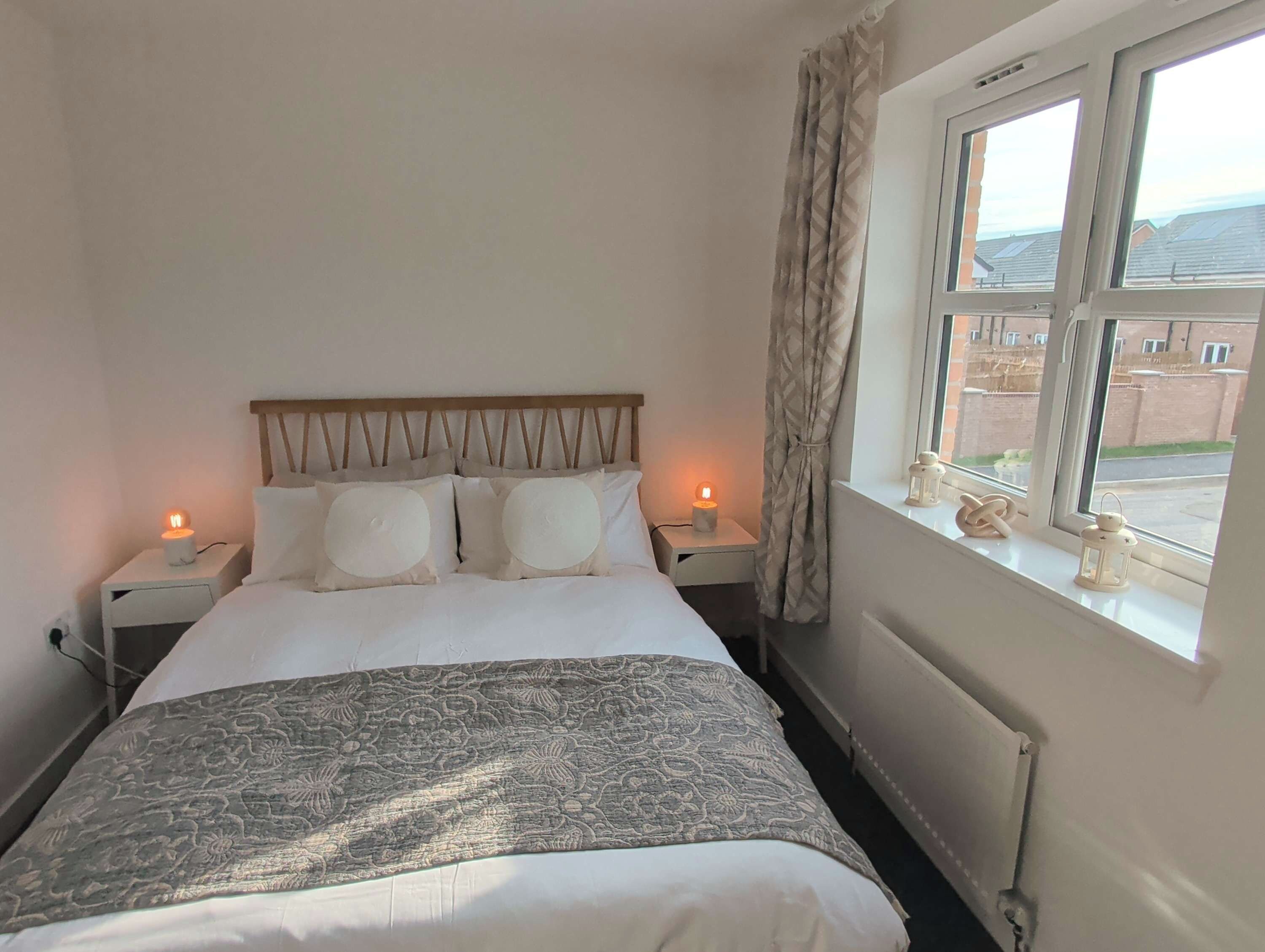 A hotel room with a bed, two bedside tables, a window with a view, and a radiator.