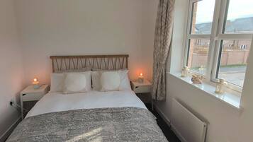 A hotel room with a bed, two bedside tables, a window with a view, and a radiator.