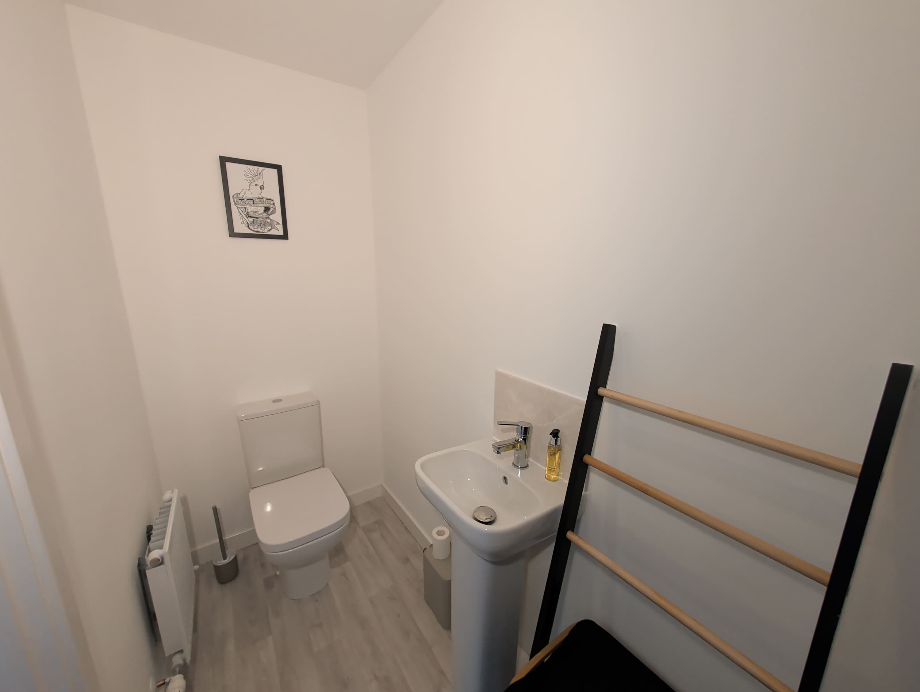 Un bagno piccolo con il water, un lavandino e un quadro appeso alla parete.