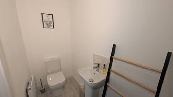 Un bagno piccolo con il water, un lavandino e un quadro appeso alla parete.