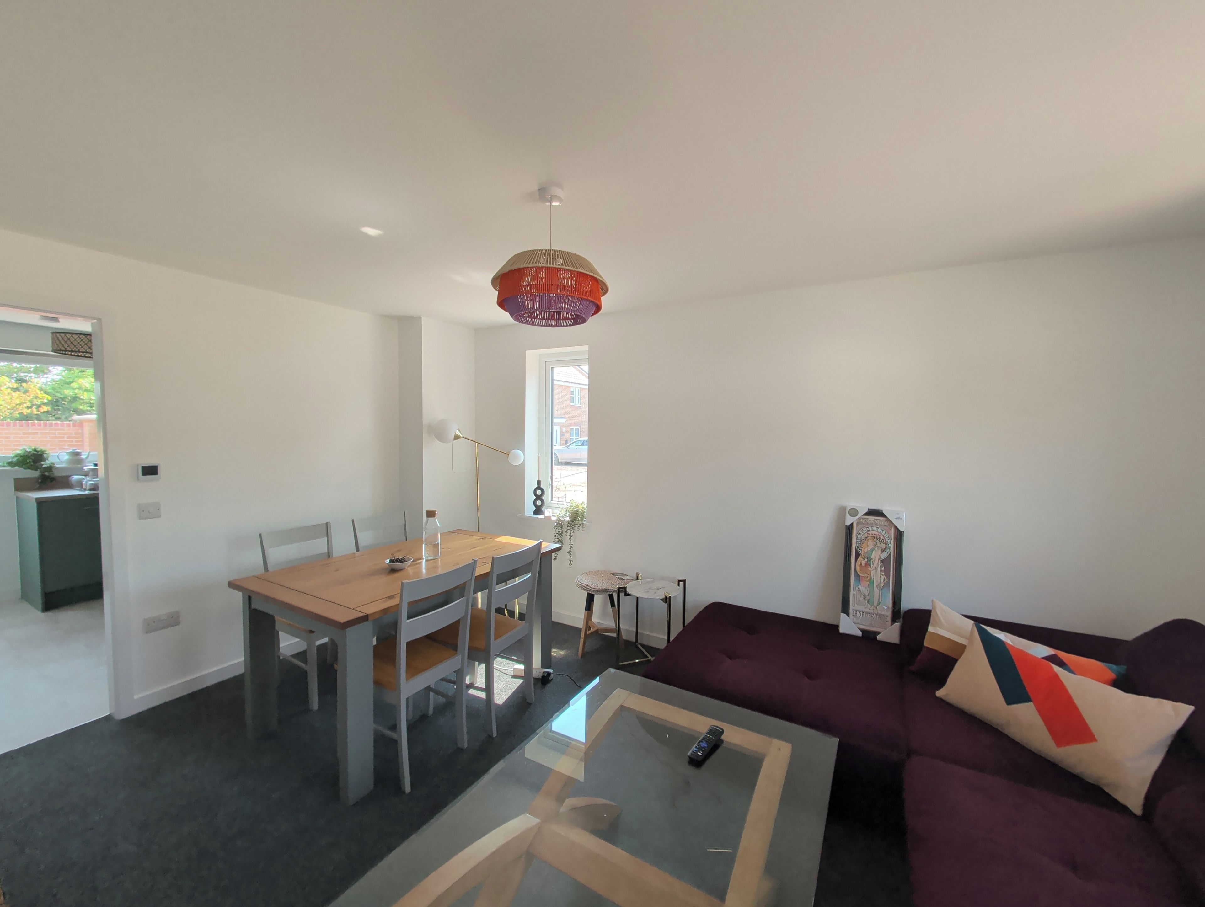 A modern living room with a dining area, a purple sofa, and a glass coffee table.