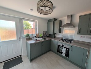 A modern kitchen with a built-in oven, a gas stove, and a window providing a view of the outside. - Stylish 2-Bed Home, Workspaces & Parking (Edinburgh)