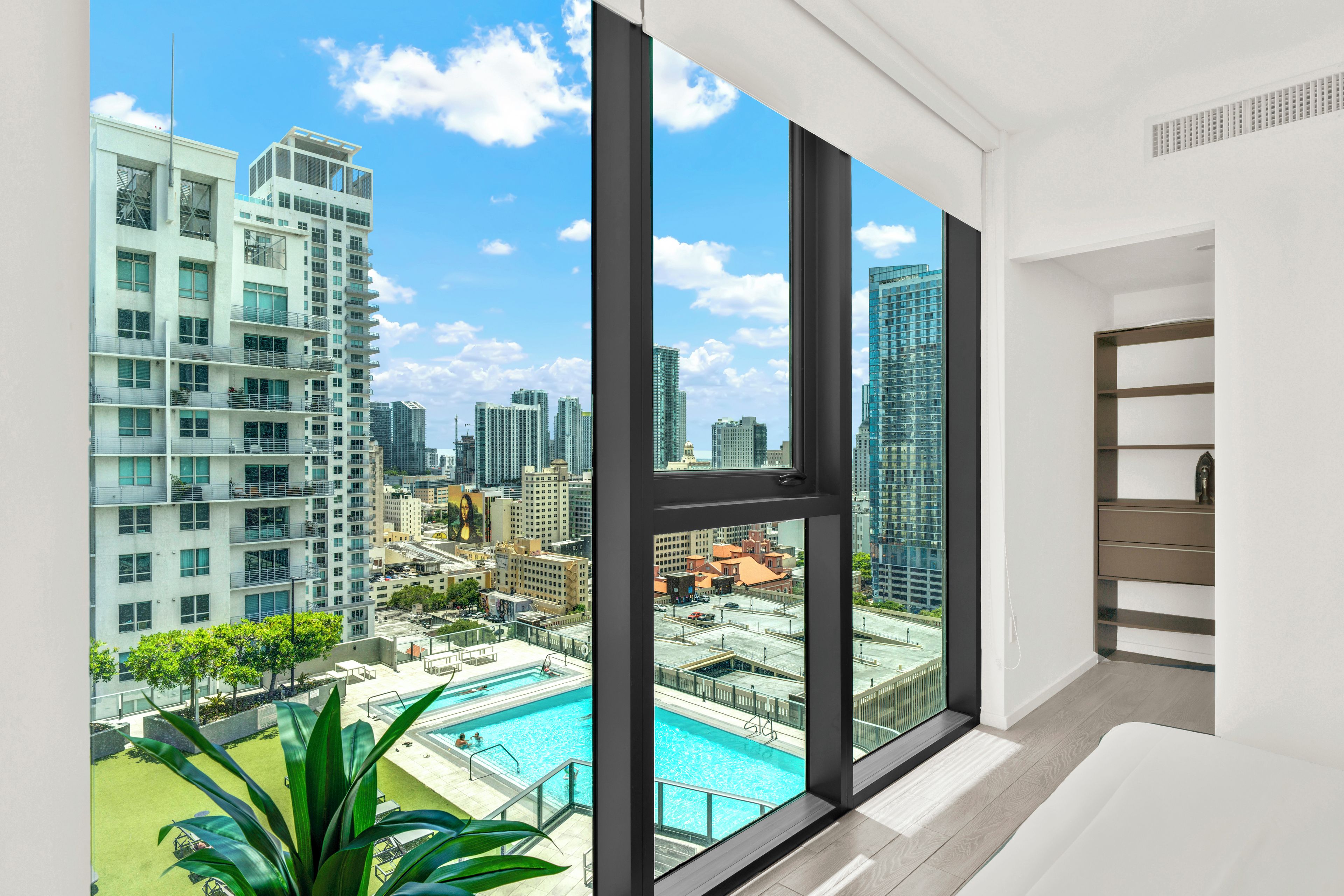 A modern apartment with large windows overlooking a cityscape and a swimming pool.