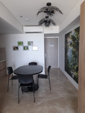 A modern dining area with a round table and four chairs, a ceiling fan, and a door with a view of a forest mural. - Enjoyable 1-bedroom hotel , ocean view with AC in charming Cartagena de Indias (Cartagena de Indias)