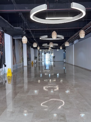 Un interior espacioso y moderno con un suelo de mármol pulido, lámparas circulares y un diseño limpio y despejado.