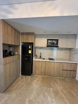 A modern kitchen with wooden cabinets, a black refrigerator, a microwave, and a marble backsplash. - Enjoyable 1-bedroom hotel , ocean view with AC in charming Cartagena de Indias (Cartagena de Indias)
