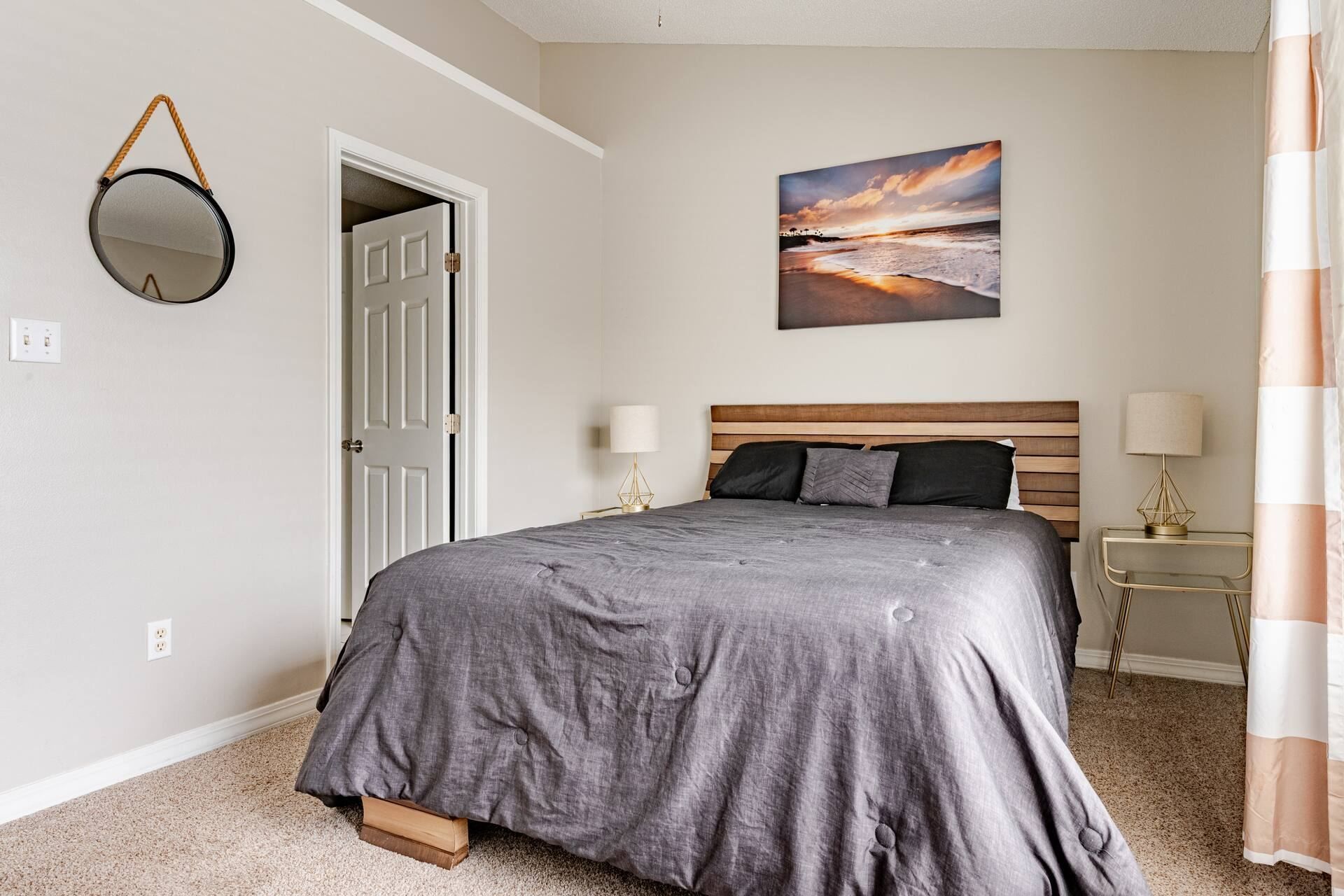 Ein Schlafzimmer mit einem Bett, einer Tür, einem Bild und einer Lampe.