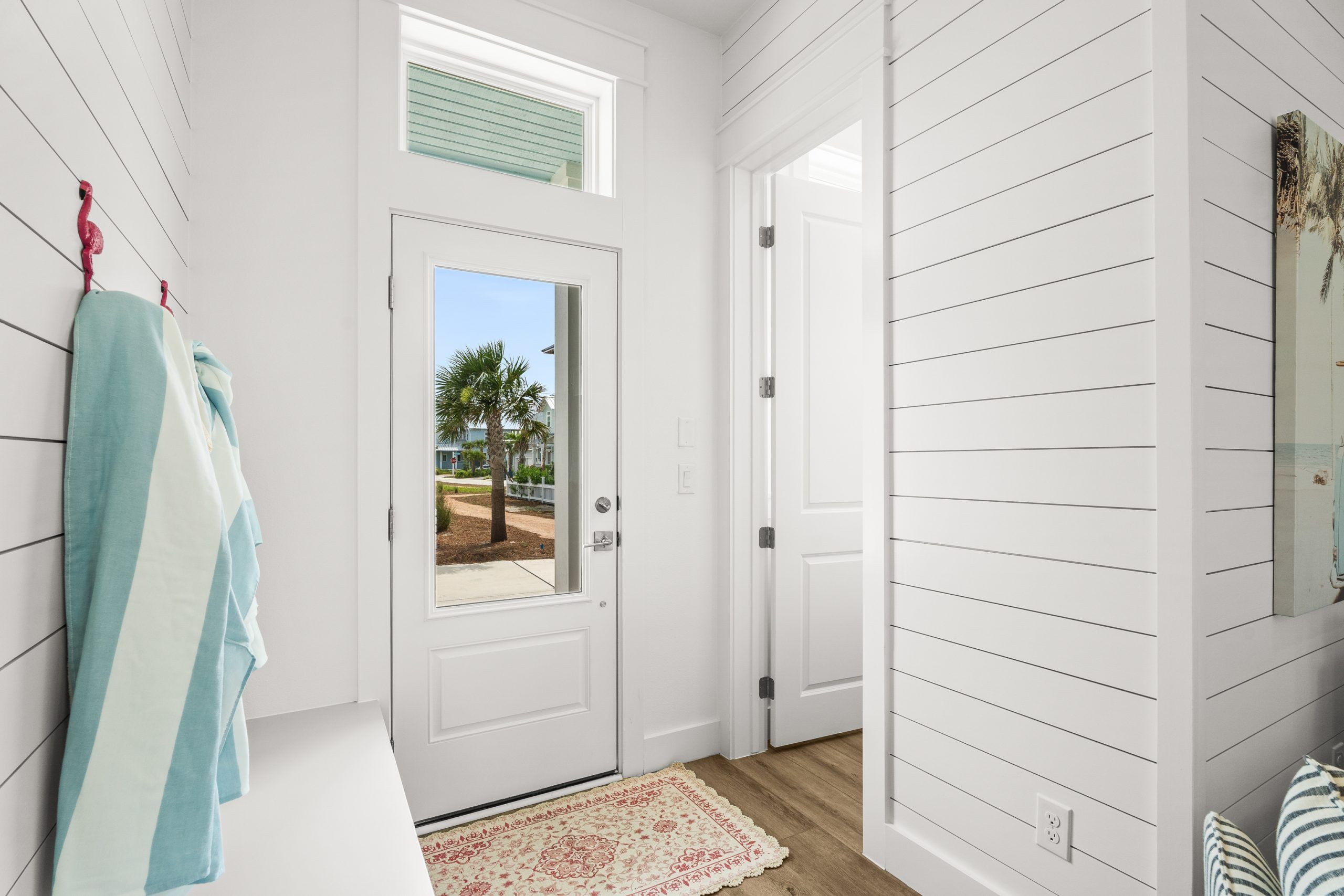 A white interior with a door leading outside, a hanging towel rack, and a patterned rug.