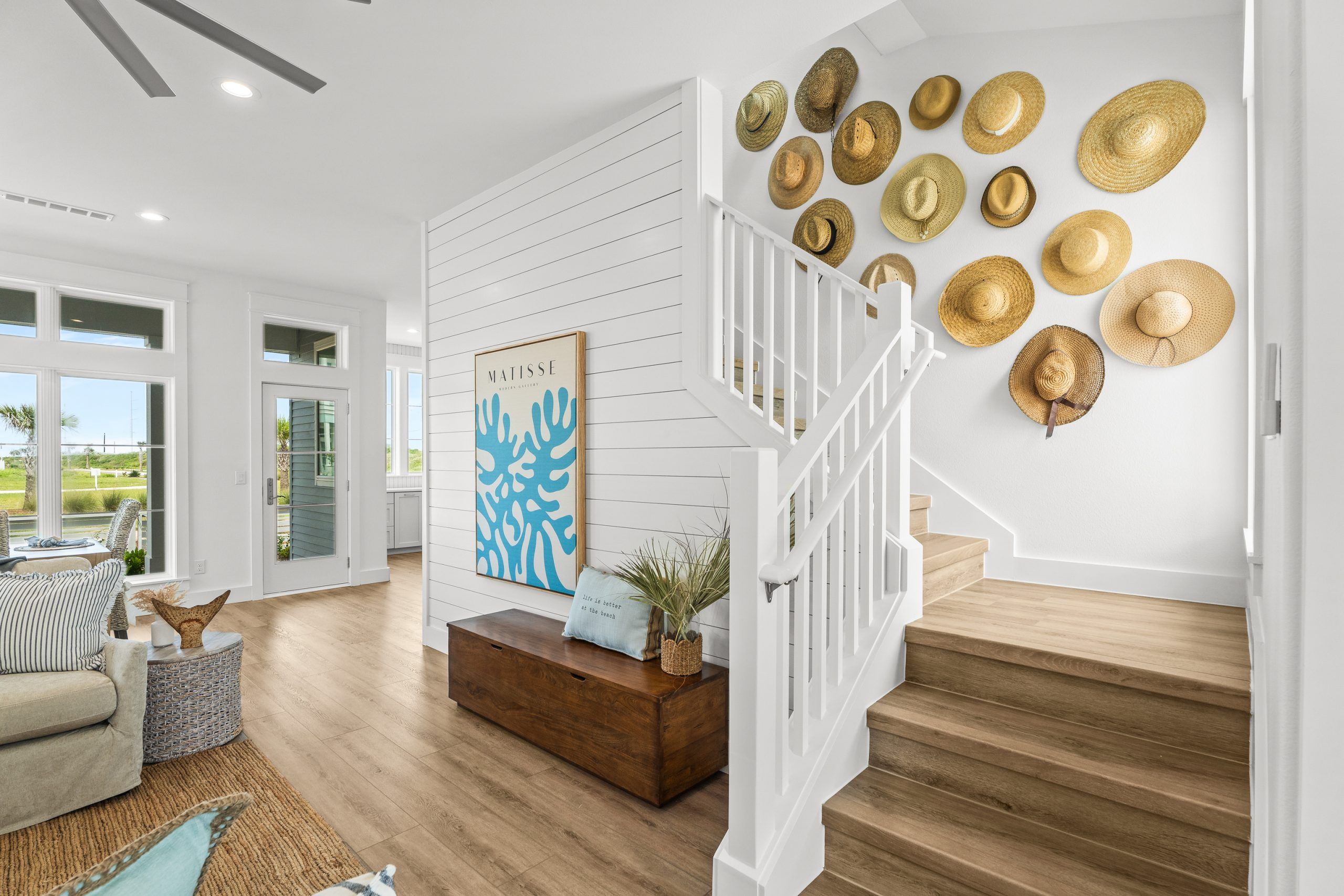 A modern interior with a staircase, a wall-mounted hat collection, and a framed artwork.