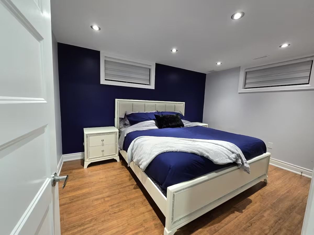 A bedroom with a bed, nightstands, and a window.