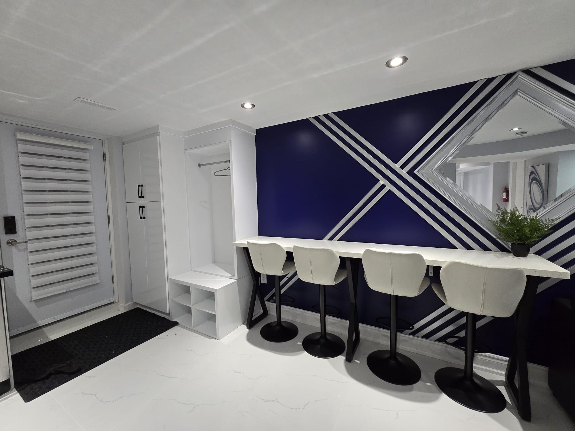A modern bathroom with a white vanity, a shower, and a dark blue accent wall with geometric patterns.