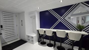 A modern bathroom with a white vanity, a shower, and a dark blue accent wall with geometric patterns.