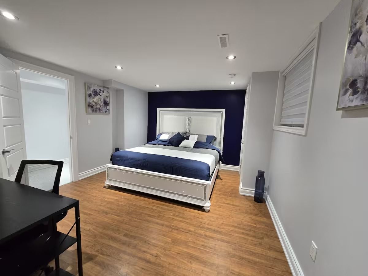 A bedroom with a bed, a desk, and a chair.