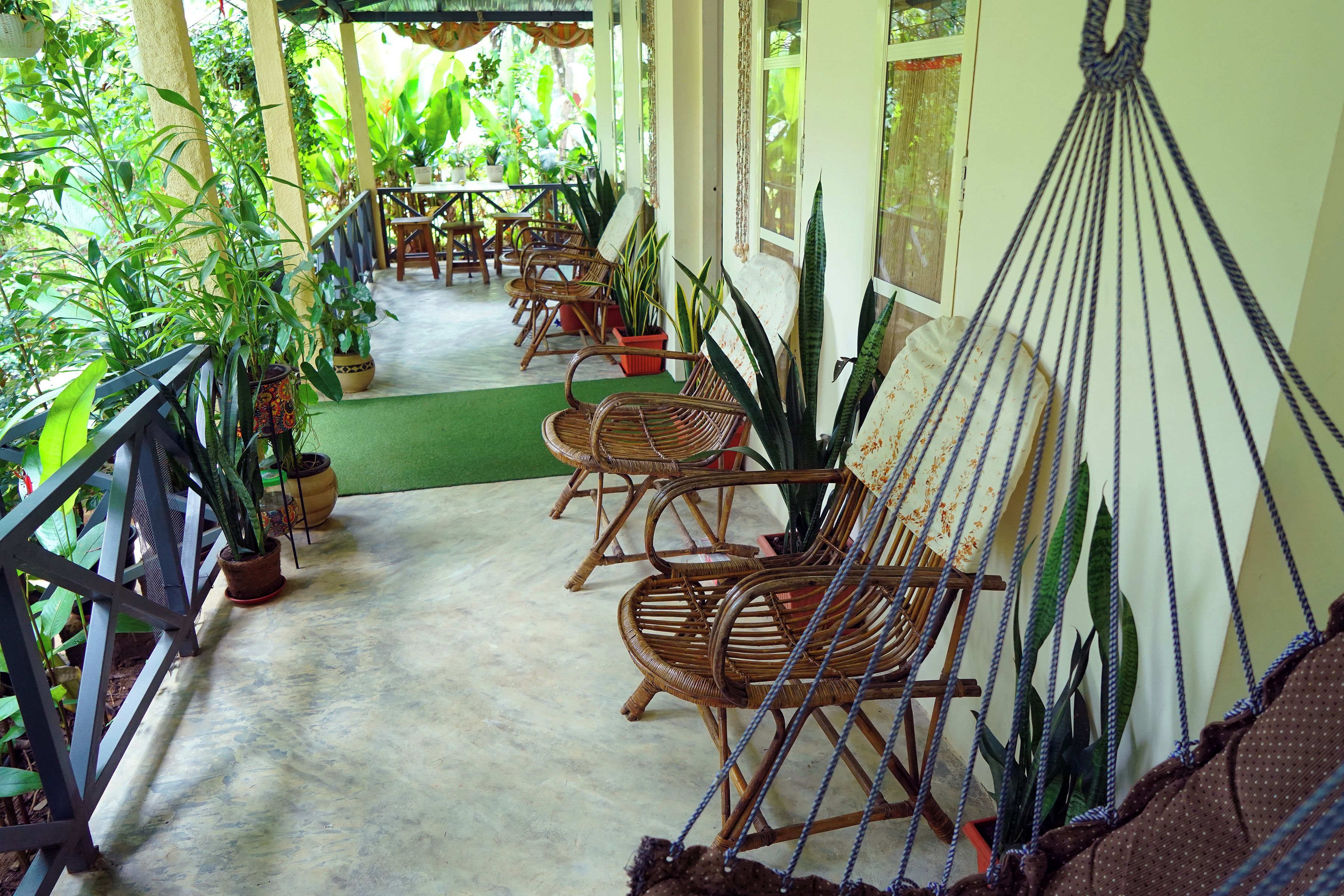 A covered outdoor area with wicker furniture and potted plants.