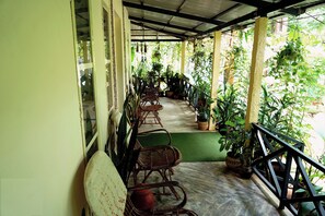 A covered porch with wicker furniture and potted plants. - Your Secret Silent Sanctuary.."Tucked in green,Guarded by the Peaks." (Kombankallu)