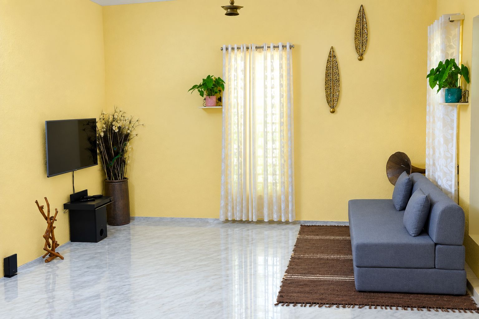 A living room with a sofa, a TV, and decorative plants.