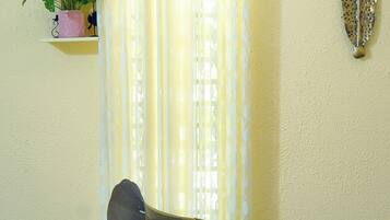 Un vieux gramophone est posé sur une petite table devant une fenêtre ornée de rideaux.