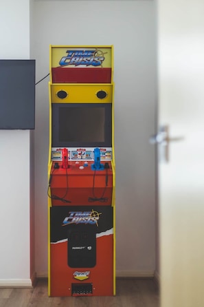 A Time Crisis arcade machine in a room with a white door and a small window. - Deluxe Two-Bedroom Vauxhall Apartment (London)
