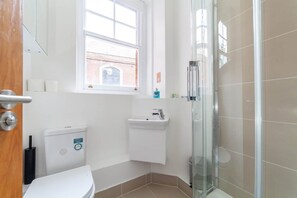 A bathroom with a toilet, sink, and glass shower enclosure.