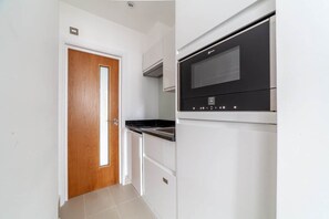 A kitchen with a microwave, oven, and a wooden door.