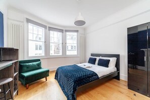 A bedroom with a bed, a green sofa, a wardrobe, and a window with a view.