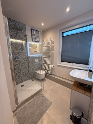 A modern bathroom with a shower, toilet, and sink. - New Listing (Essen)