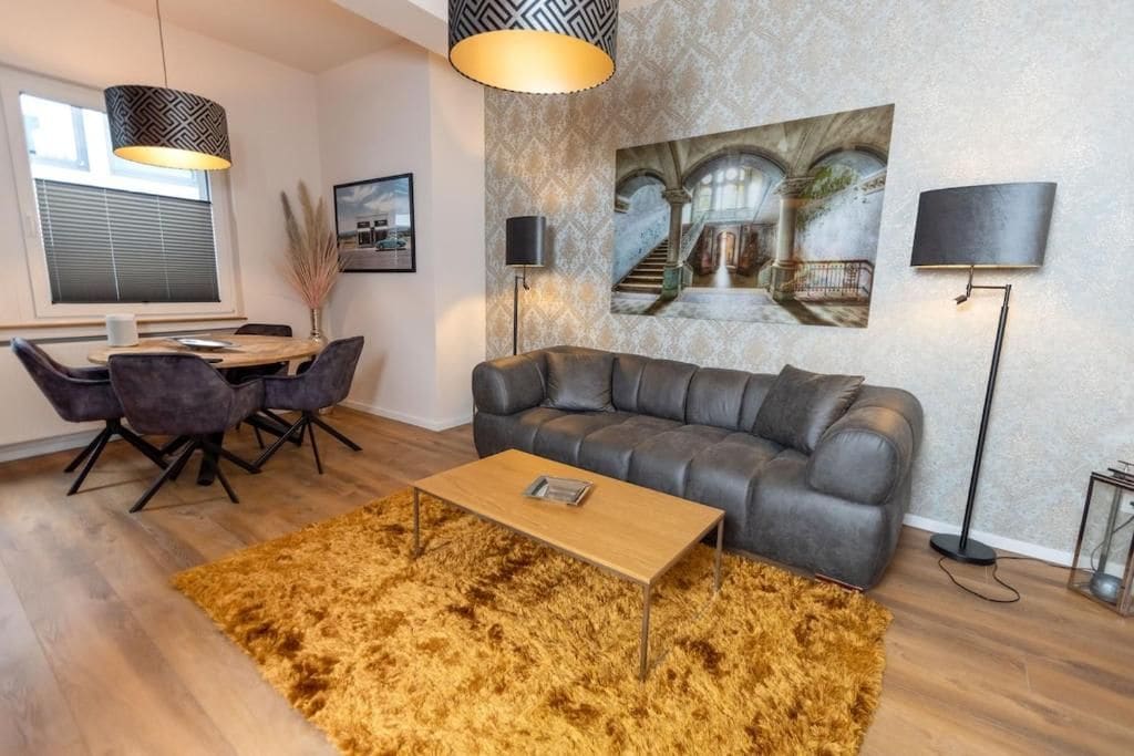 A modern living room with a sofa, coffee table, and dining area.