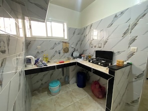 Una cucina compatta con piano cottura a gas, forno a microonde e lavandino.