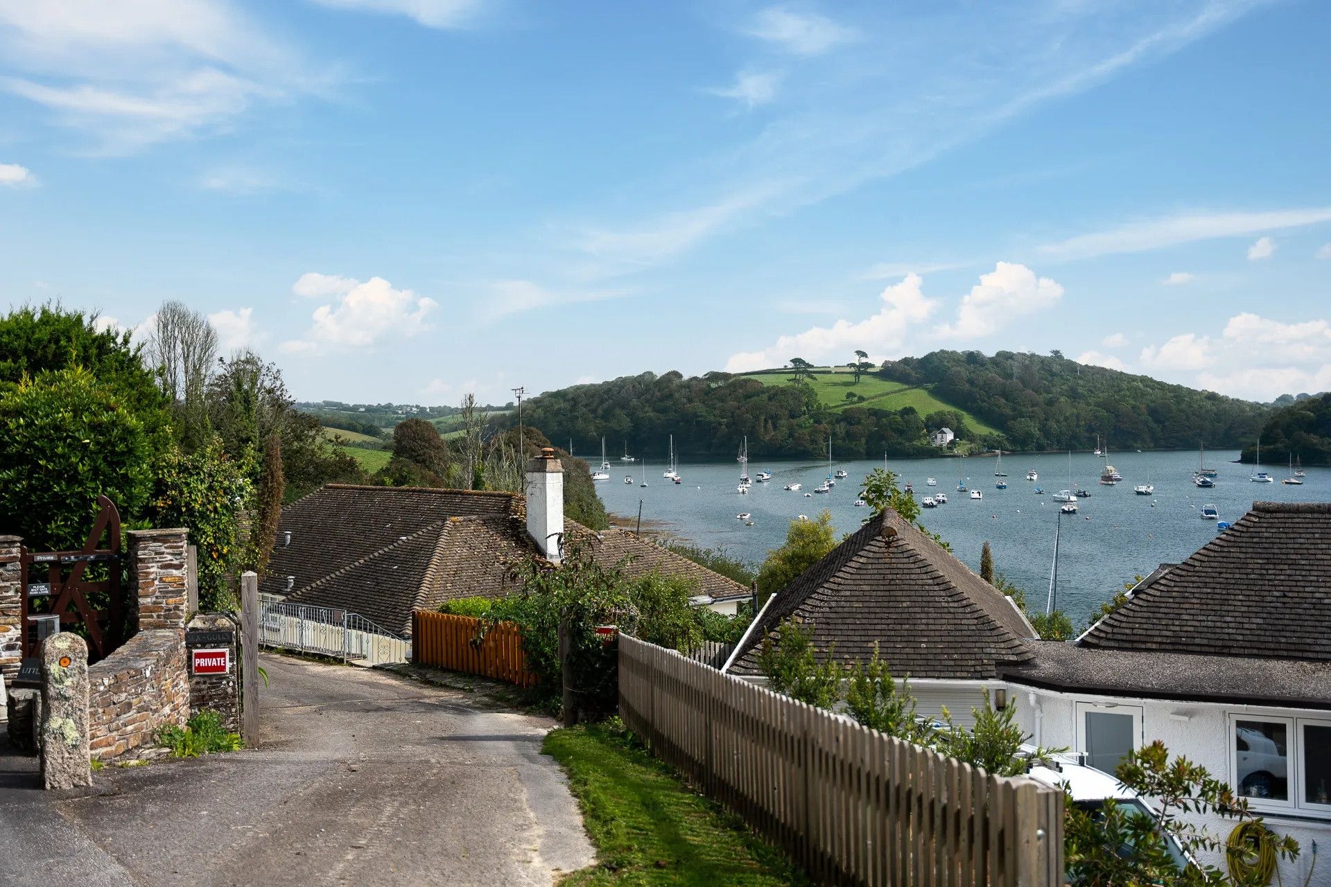 Un village côtier doté d’une propriété privée, d’un mur en pierre et offrant une vue sur les bateaux qui naviguent sur l’eau.