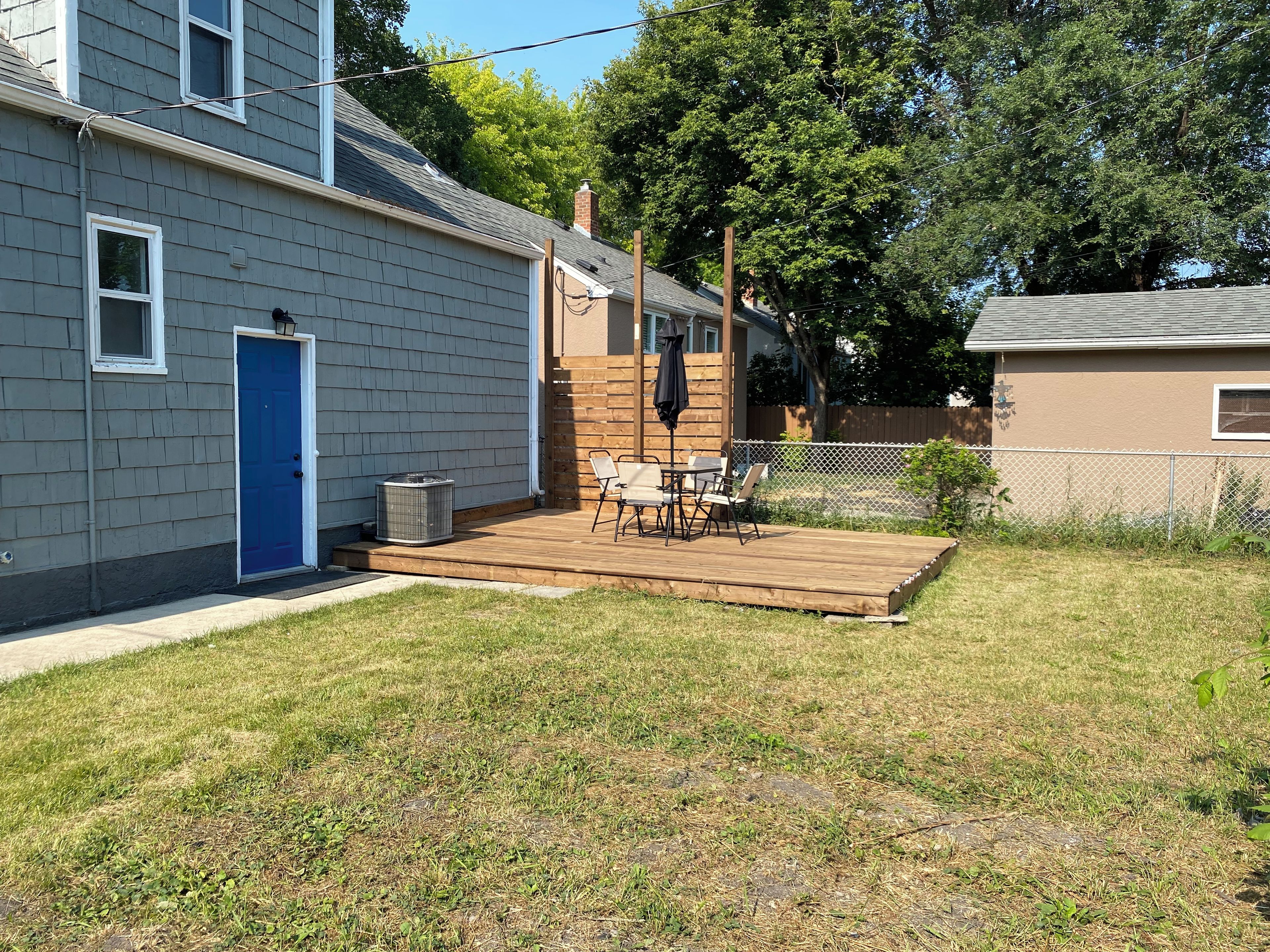A residential property with a deck, a blue door, and a fenced backyard.
