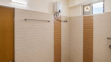 A bathroom with a shower, a towel rack, and a window.