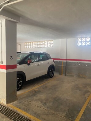 Eine Tiefgarage mit einem weißen Auto in einem dafür vorgesehenen Stellplatz.