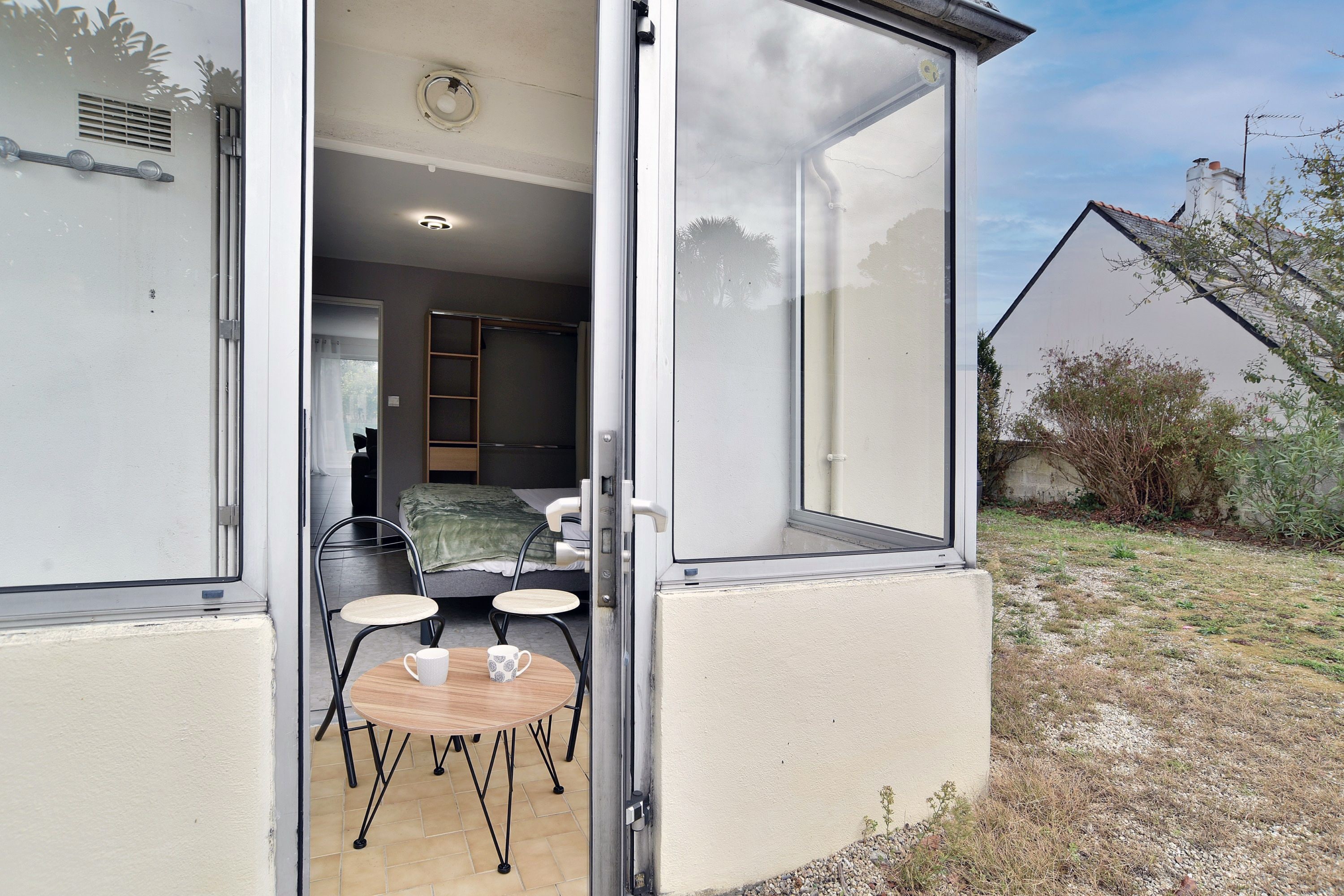 Une chambre avec un lit, une table entourée de chaises et une fenêtre donnant sur un jardin.